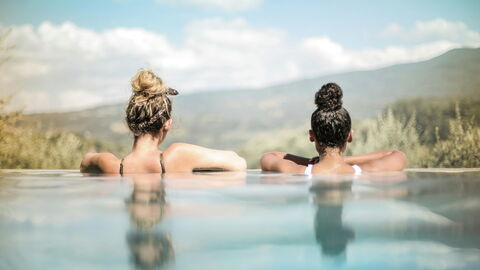 Zwei Frauen schauen aus einem Infinity-Pool heraus