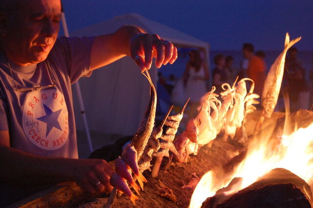 Ein Mann grillt Fisch am Strand